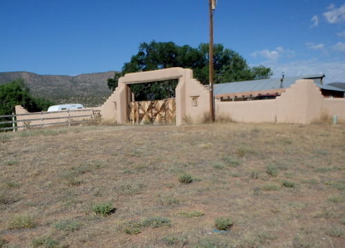 GDMBR: Nice adobe wall and wood pattern gate.